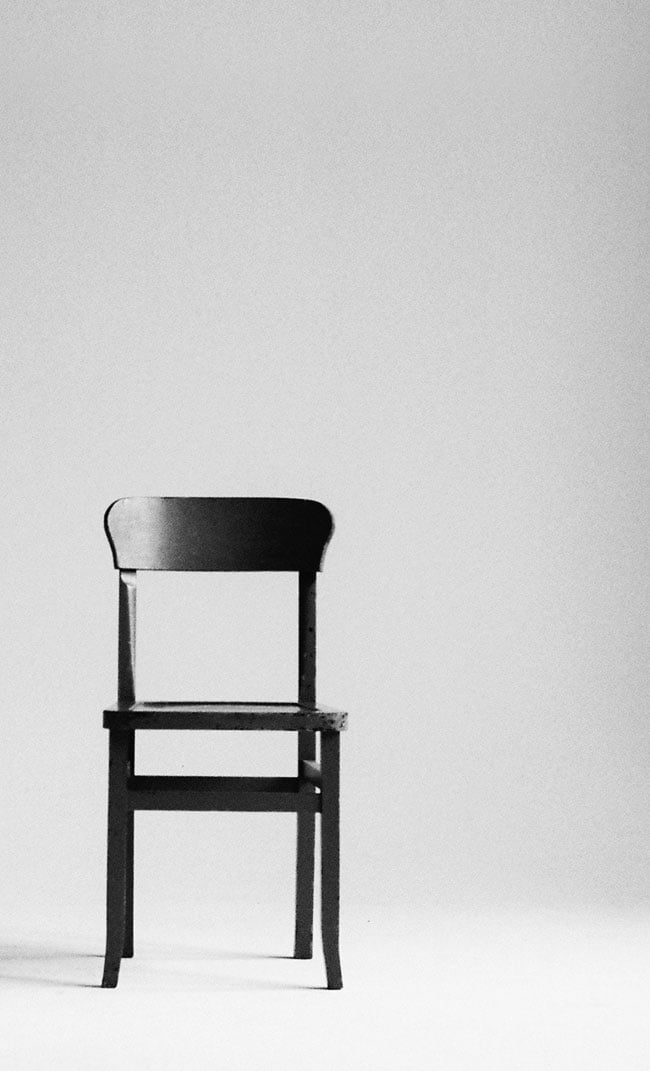 white background with an empty dark wood chair on the lower right